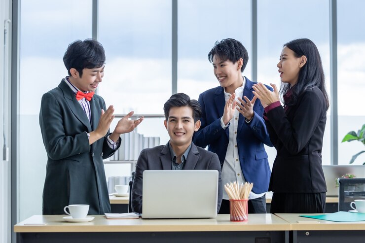 successful-happy-workers-group-asian-business-people-with-diverse-genders-lgbt-clap-hands-congratulate-businessman-see-successful-business-plan-laptop-computer-meeting-room_29332-3554